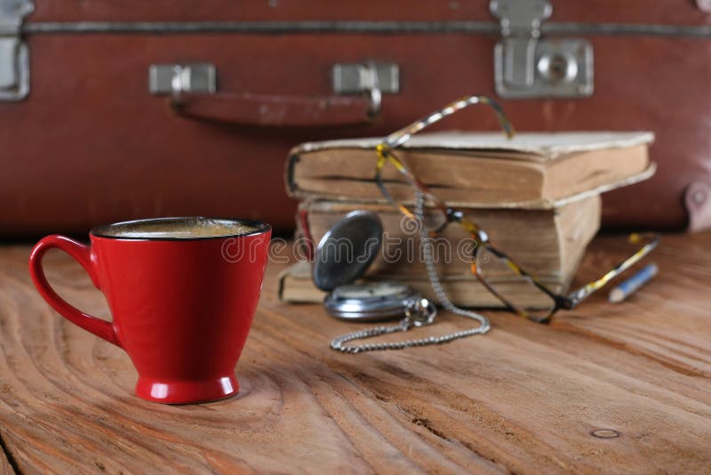 Kopp kaffe, tappningresväska, klockor, exponeringsglas och gamla böcker fotografering för bildbyråer