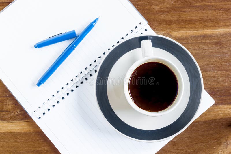 Kopp kaffe över anteckningsboken på trätabellen arkivfoto Kopp kaffe över anteckningsboken på trätabellen arkivfoto