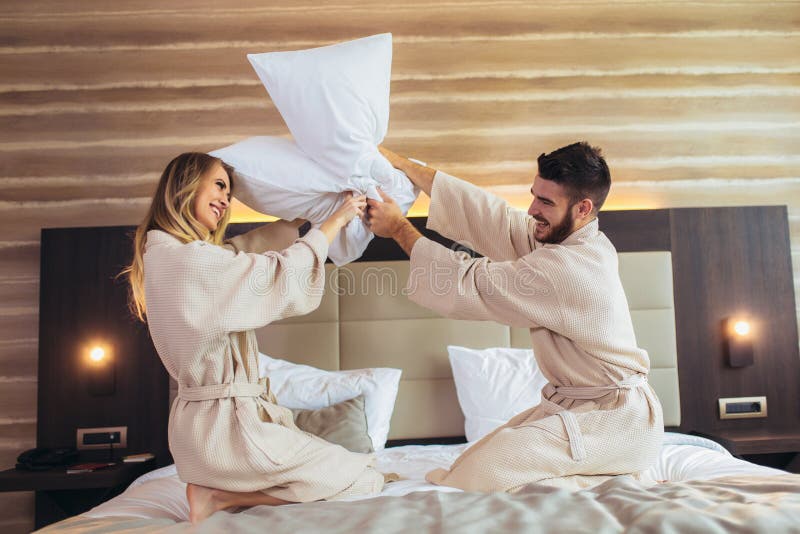 Koppla ihop att ha kuddekamp i hotellrum arkivbilder Koppla ihop att ha kuddekamp i hotellrum arkivbilder