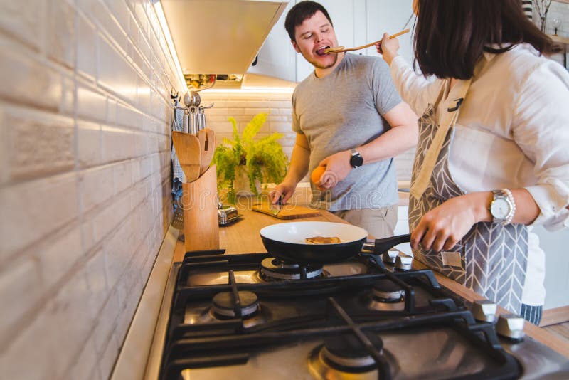 Koppla ihop att laga mat tillsammans på köket steka pannkakor som klipper apelsinen Avsmakningmat arkivfoto Koppla ihop att laga mat tillsammans på köket steka pannkakor som klipper apelsinen Avsmakningmat arkivfoto