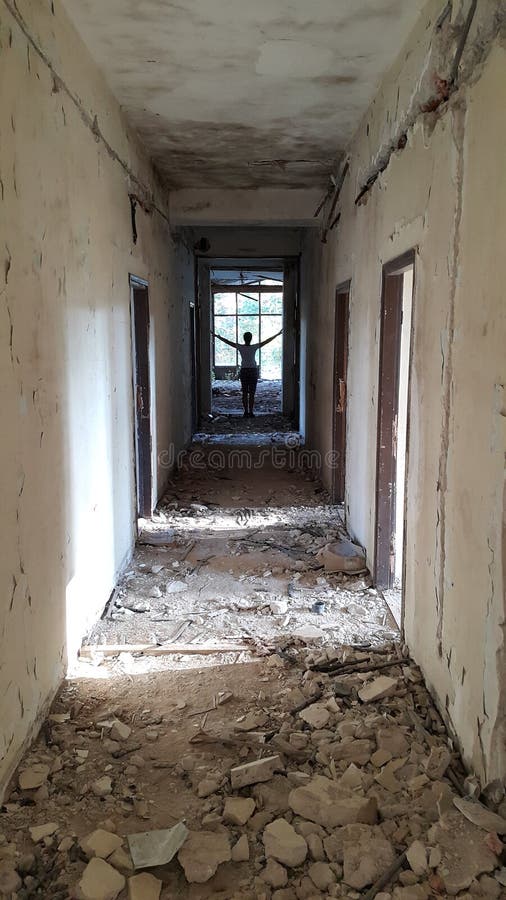 Empty corridor with interesting lighting of the old, not used, abandoned, decaying hotel Tara on the Tara mountain in Western Serbia, that was used for accommodation of school children in the 80s, with figure in the distance. Empty corridor with interesting lighting of the old, not used, abandoned, decaying hotel Tara on the Tara mountain in Western Serbia, that was used for accommodation of school children in the 80s, with figure in the distance.