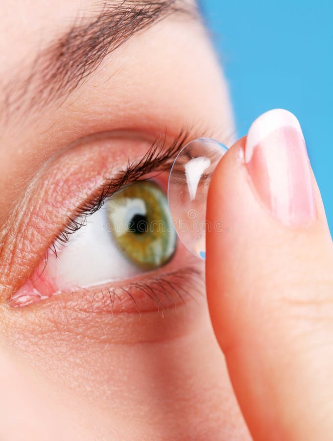 Corrective lens on a finger near an eye on a blue background. Corrective lens on a finger near an eye on a blue background