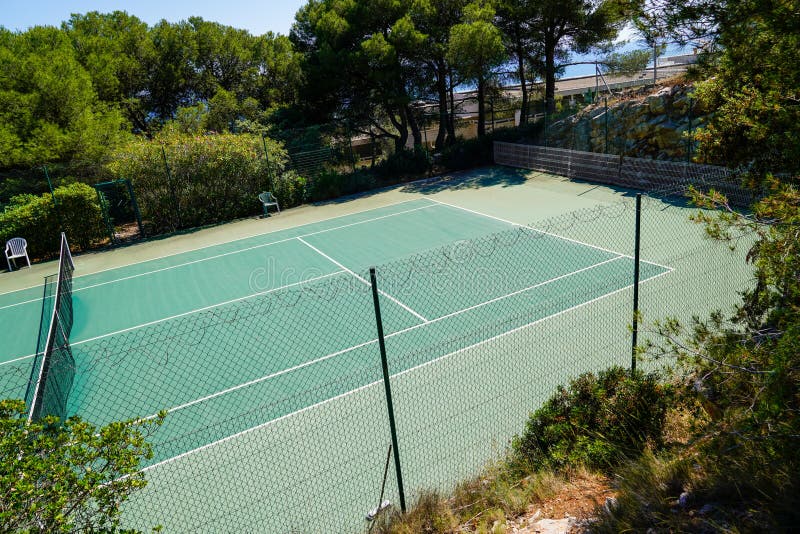 A tennis courts green private through wire mesh fence in home garden. A tennis courts green private through wire mesh fence in home garden