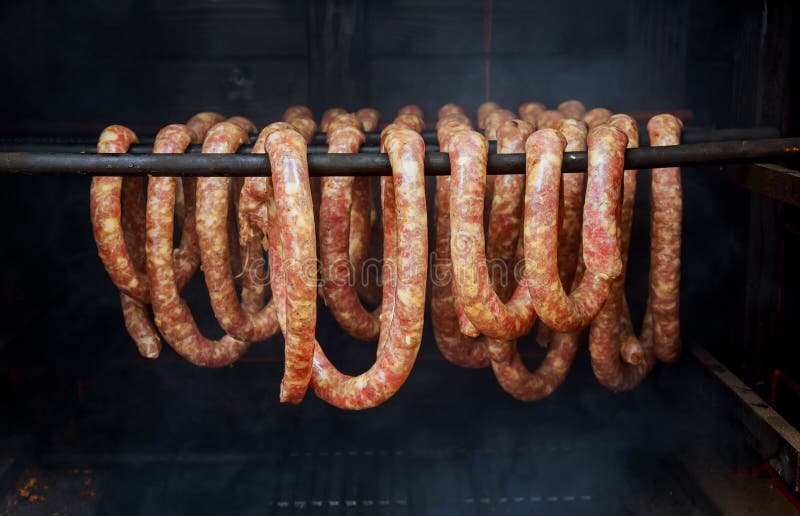 sausages and bacon being smoked in barrel-shaped smoker. sausages and bacon being smoked in barrel-shaped smoker