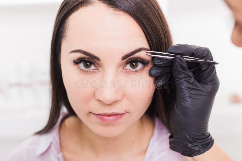 Kosmetiker zupft die Augenbrauen einer jungen Frau mit Pinzette stockfoto Kosmetiker zupft die Augenbrauen einer jungen Frau mit Pinzette stockfoto