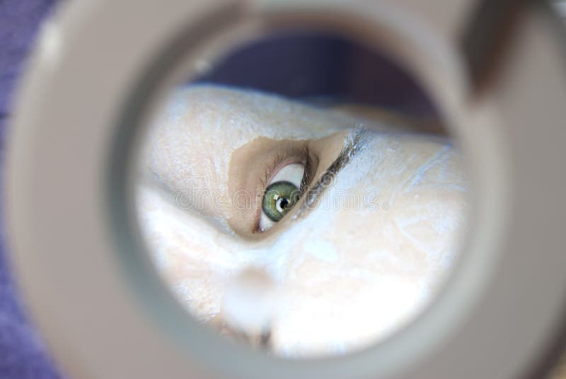 Kosmetische Behandlung durch Vergrößerungsglas stockfotografie Kosmetische Behandlung durch Vergrößerungsglas stockfotografie