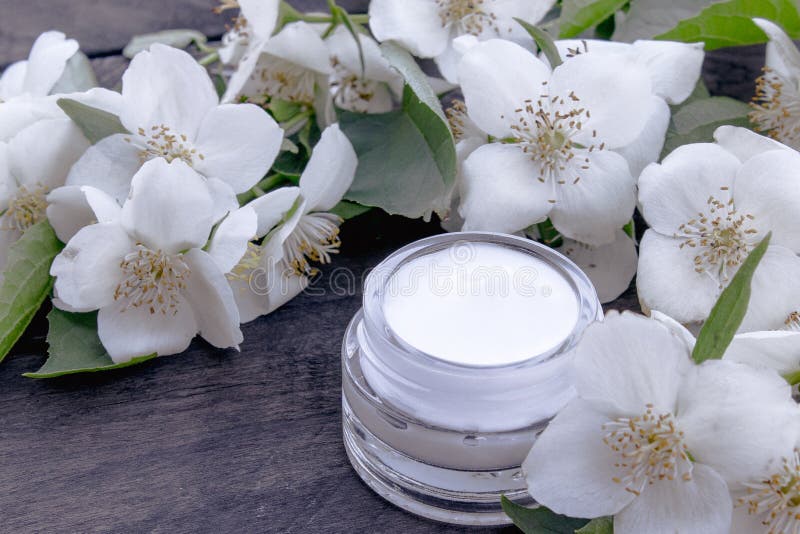 Kosmetische Creme in einem Glasgefäß mit Jasminblumen auf einem hölzernen Hintergrund lizenzfreie stockfotos Kosmetische Creme in einem Glasgefäß mit Jasminblumen auf einem hölzernen Hintergrund lizenzfreie stockfotos