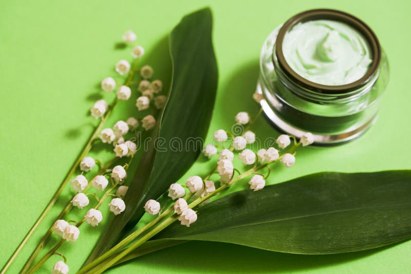 kosmetische Creme- und Maiglöckchenblumen auf einem grünen Hintergrund stockfoto kosmetische Creme- und Maiglöckchenblumen auf einem grünen Hintergrund stockfoto
