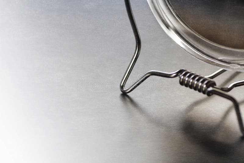Kosmetiskt spegelfragment som stiliseras, på grå färger, med reflexioner arkivbild Kosmetiskt spegelfragment som stiliseras, på grå färger, med reflexioner arkivbild