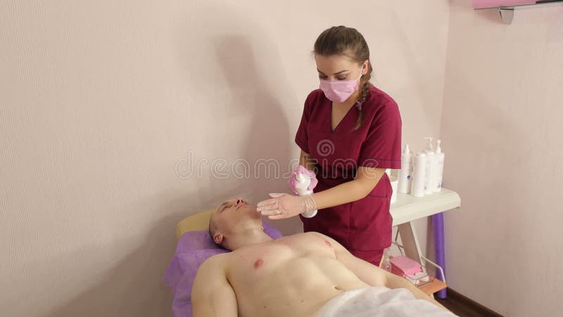 Kosmetologen behandlar huden av en man efter depilation av sockra f?r br?st