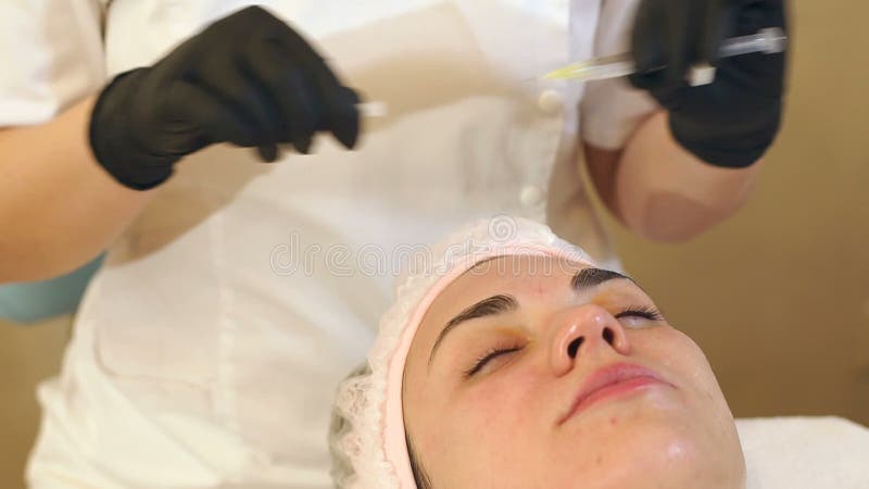 Kosmetologen tar bort locket från injektionssprutan med hyaluronic syra