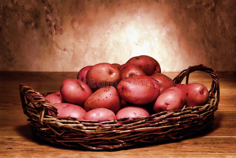 Organic red skin potatoes in an old wicker basket on a wood table. Organic red skin potatoes in an old wicker basket on a wood table