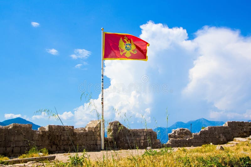 KOTOR, ЧЕРНОГОРИЯ - 12-ОЕ ИЮНЯ 2015: Развевать в флаге ветра Черногории Стена древней крепости над Kotor стоковые изображения rf KOTOR, ЧЕРНОГОРИЯ - 12-ОЕ ИЮНЯ 2015: Развевать в флаге ветра Черногории Стена древней крепости над Kotor стоковые изображения rf