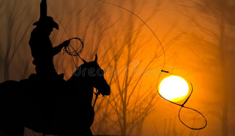Cowboy on horse with Lasso roping the sun against golden soft blurred background. Cowboy on horse with Lasso roping the sun against golden soft blurred background.