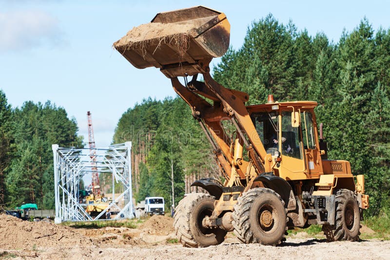 Koło ładowacza maszynowy rozładunkowy piasek przy eathmoving pracuje przy budową obraz stock Koło ładowacza maszynowy rozładunkowy piasek przy eathmoving pracuje przy budową obraz stock