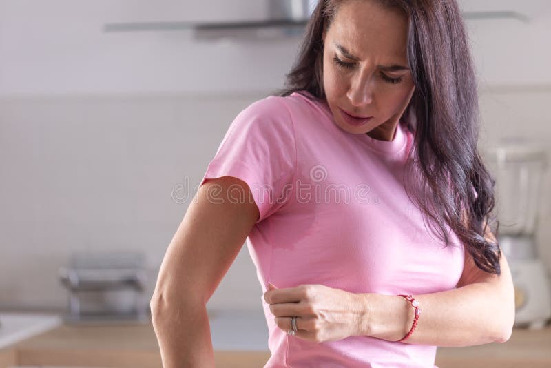 Kraftig svettning synlig genom fläckar på en rosa skjorta av en ung kvinna arkivfoto