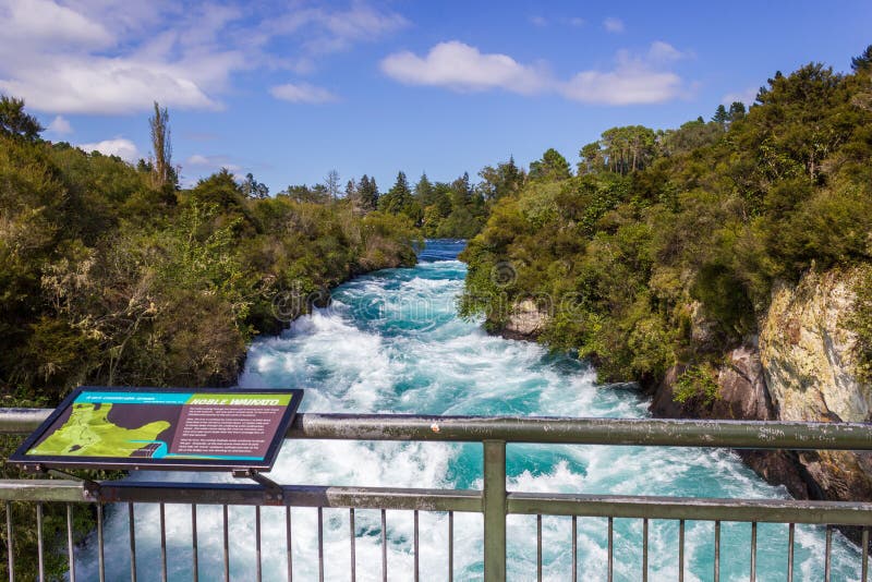 Kraftiga Huka nedgångar med ett tecken med information om nedgångarna, på den Waikato floden nära Taupo den norr ön Nya Zeeland royaltyfri foto Kraftiga Huka nedgångar med ett tecken med information om nedgångarna, på den Waikato floden nära Taupo den norr ön Nya Zeeland royaltyfri foto