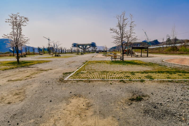 Sejong, South Korea; April 1, 2020: Landscape of public park with new bridge under construction in background. Sejong, South Korea; April 1, 2020: Landscape of public park with new bridge under construction in background