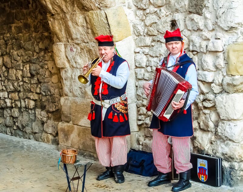 Krakau, Polen - 19 nov., 2017: De musici in traditionele Poolse kleren presteren voor toeristen op een authentieke manier stock afbeelding Krakau, Polen - 19 nov., 2017: De musici in traditionele Poolse kleren presteren voor toeristen op een authentieke manier stock afbeelding