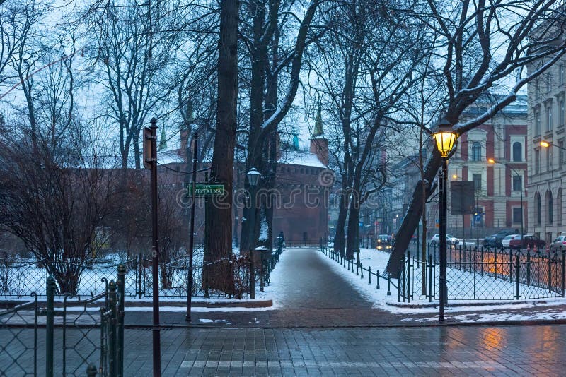 KRAKOW, POLAND - JANUARY 06, 2016: Evening winter view of the city park Planty and ancient Barbakan building in historical part of Krakow