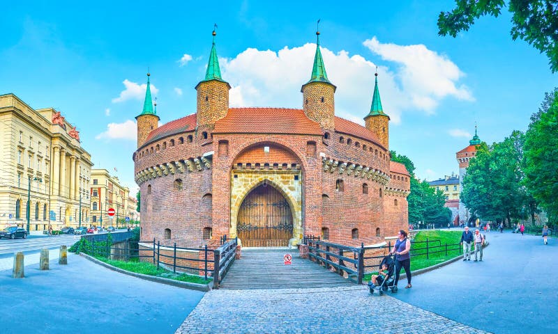 KRAKOW, POLAND - JUNE 11, 2018: The view on Barbakan with preserved part of city moat, surrounded with lush park and edifices of modern neighborhood, on June 11 in Krakow. KRAKOW, POLAND - JUNE 11, 2018: The view on Barbakan with preserved part of city moat, surrounded with lush park and edifices of modern neighborhood, on June 11 in Krakow