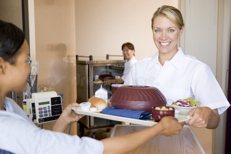 Krankenschwester, die einem Patienten eine Mahlzeit in seinem Bett dient stockbild Krankenschwester, die einem Patienten eine Mahlzeit in seinem Bett dient stockbild