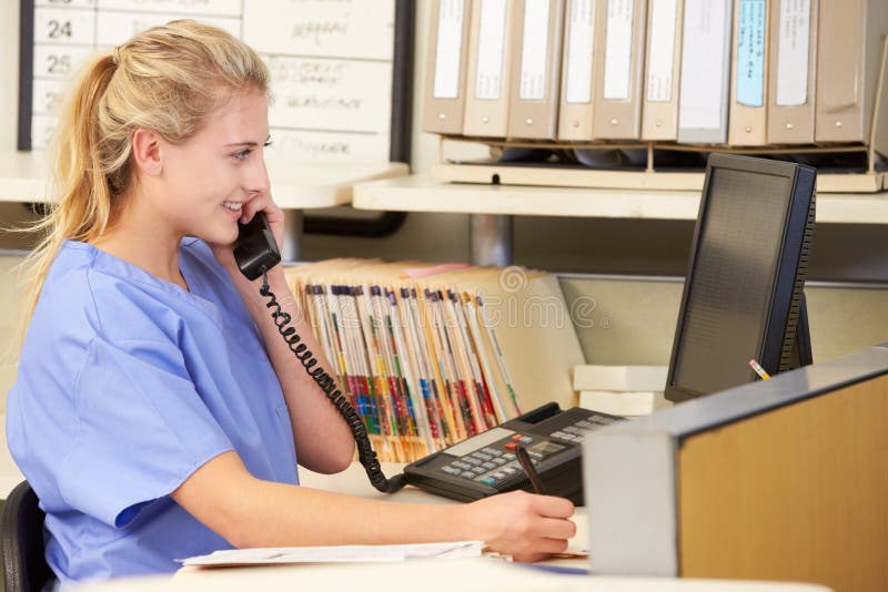 Krankenschwester, die Telefon-Aufruf an der Krankenschwester-Station macht stockbild Krankenschwester, die Telefon-Aufruf an der Krankenschwester-Station macht stockbild
