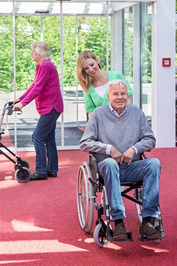 Krankenschwester Pushing Senior Man im Rollstuhl in der Lobby stockfoto Krankenschwester Pushing Senior Man im Rollstuhl in der Lobby stockfoto