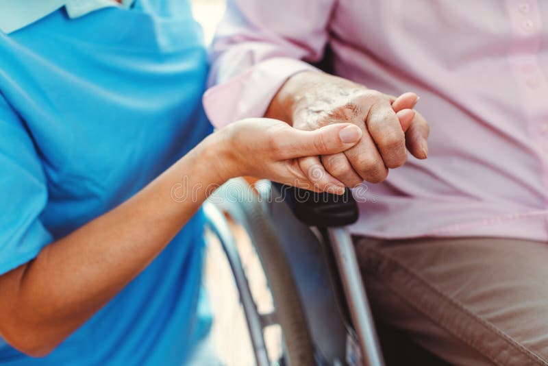 Krankenschwester tröstet eine ältere Frau im Pflegeheim, die ihre Hand hält