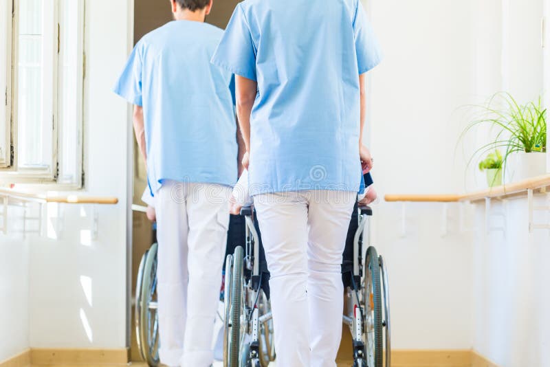 Krankenschwestern, die Senioren im Rollstuhl durch Pflegeheim drücken