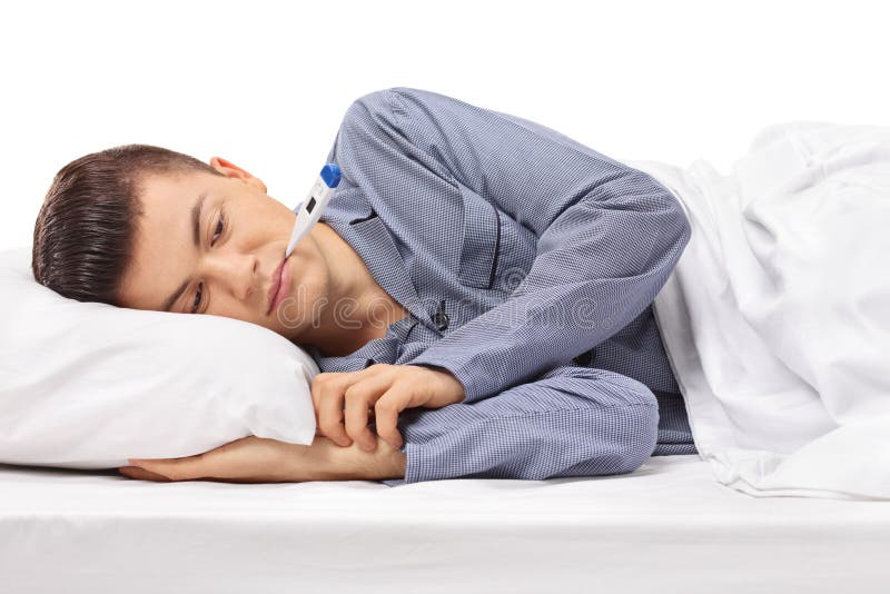 Sick teenager with a thermometer in his mouth lying in bed isolated on white background. Sick teenager with a thermometer in his mouth lying in bed isolated on white background