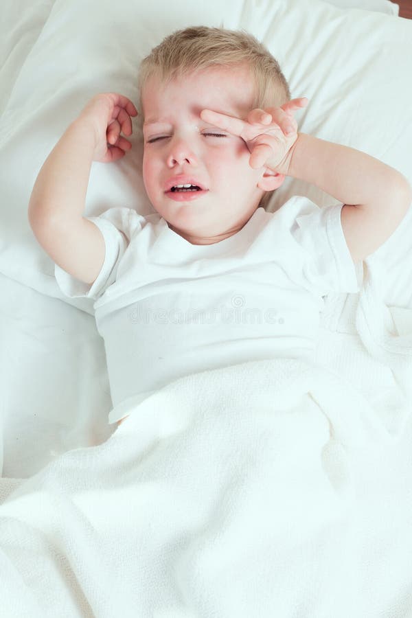 Kranker Kleinkindjunge, der im Bett schreit stockfotos