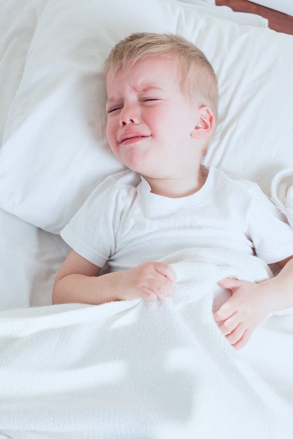 Kranker Kleinkindjunge, der im Bett schreit lizenzfreie stockbilder