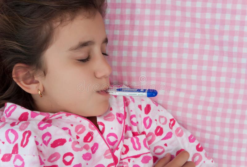 Portrait of a beautiful hispanic girl sick with fever with a thermometer in her mouth laying on a bed with pink sheets. Portrait of a beautiful hispanic girl sick with fever with a thermometer in her mouth laying on a bed with pink sheets