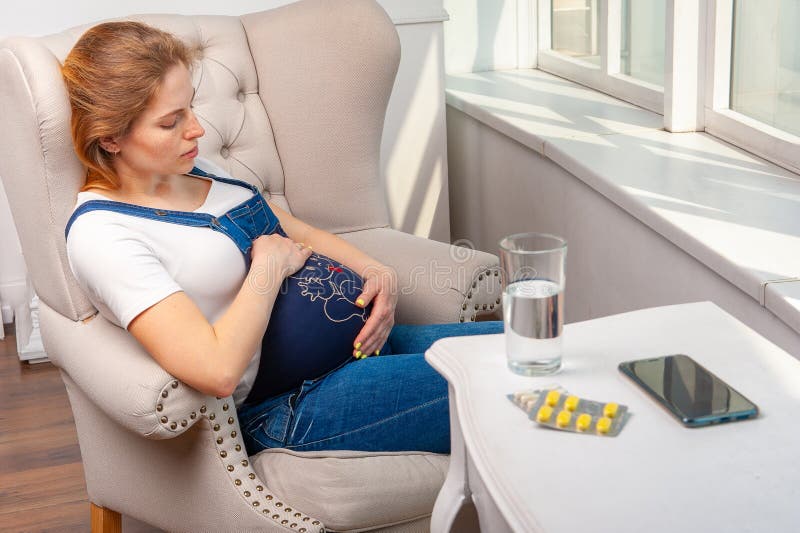 Krankheit während der Schwangerschaft Frau, die zu Hause sitzt und medizinische Drogen nimmt lizenzfreie stockfotografie Krankheit während der Schwangerschaft Frau, die zu Hause sitzt und medizinische Drogen nimmt lizenzfreie stockfotografie