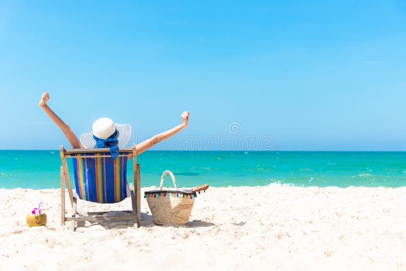 Summer Vacation. Beautiful young asian woman relaxing and happy on beach chair with cocktail coconut juice in holiday summer, blue sky background. Travel and lifestyle Concept. Summer Vacation. Beautiful young asian woman relaxing and happy on beach chair with cocktail coconut juice in holiday summer, blue sky background. Travel and lifestyle Concept