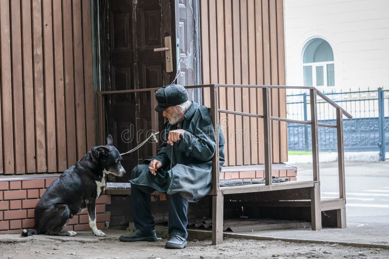Krasnoyarsk Ryssland, 24 juli, 2019: en enslig farfar med hans hund sitter ledset och röker cigaretten Mjuk fokus, suddighet arkivfoton Krasnoyarsk Ryssland, 24 juli, 2019: en enslig farfar med hans hund sitter ledset och röker cigaretten Mjuk fokus, suddighet arkivfoton