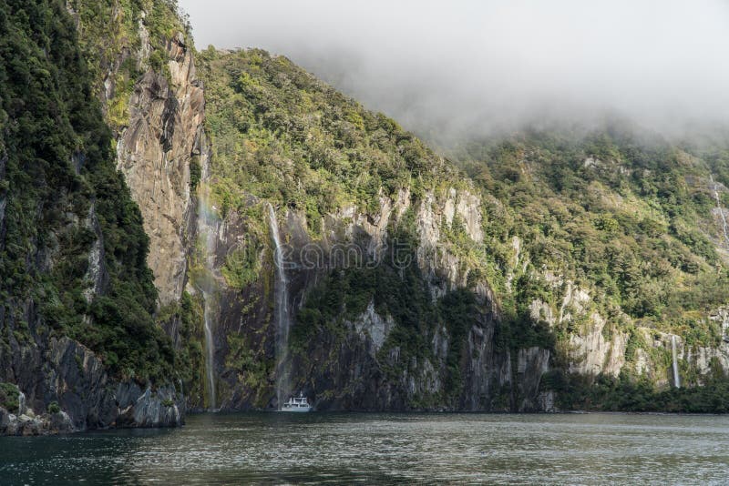Kreuzschiff in Milford Sound unter Wasserfall in Neuseeland stockfotos Kreuzschiff in Milford Sound unter Wasserfall in Neuseeland stockfotos