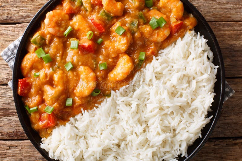 Creole shrimp Etouffee dish with celery, onion and pepper cooked in roux sauce served with rice close-up in a plate on the table. Horizontal top view from above. Creole shrimp Etouffee dish with celery, onion and pepper cooked in roux sauce served with rice close-up in a plate on the table. Horizontal top view from above