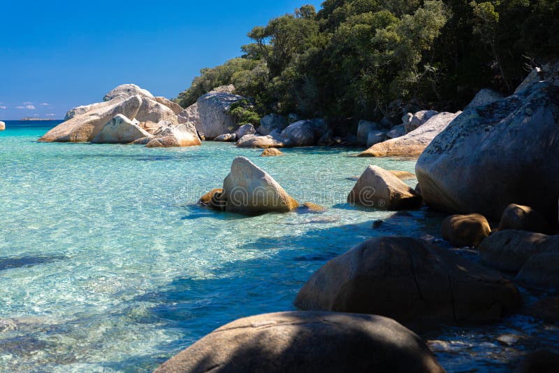 Kristallklares türkisfarbenes Wasser und große, glatte Felsen auf einem ruhigen Strand umgeben von Natur. ein idealer Ort zum Ents lizenzfreie stockfotografie
