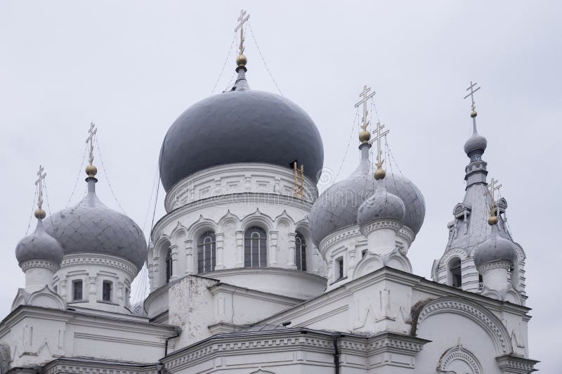 Kristen ortodox vit kyrka med silver och gråa kupoler med guld- kors Lugna grå himmel över royaltyfri foto Kristen ortodox vit kyrka med silver och gråa kupoler med guld- kors Lugna grå himmel över royaltyfri foto