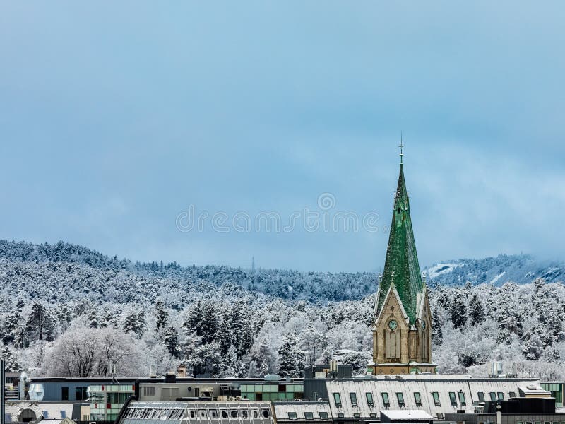 Winter in Kristiansand City. Snow covered church tower in the city, emerging above the roofs of the city. Kristiansand, Norway in Europe. Winter in Kristiansand City. Snow covered church tower in the city, emerging above the roofs of the city. Kristiansand, Norway in Europe