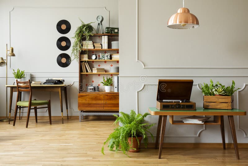 Kroonluchter boven uitstekende grammofoon en doos met groene installaties in het uitstekende binnenland van het huisbureau