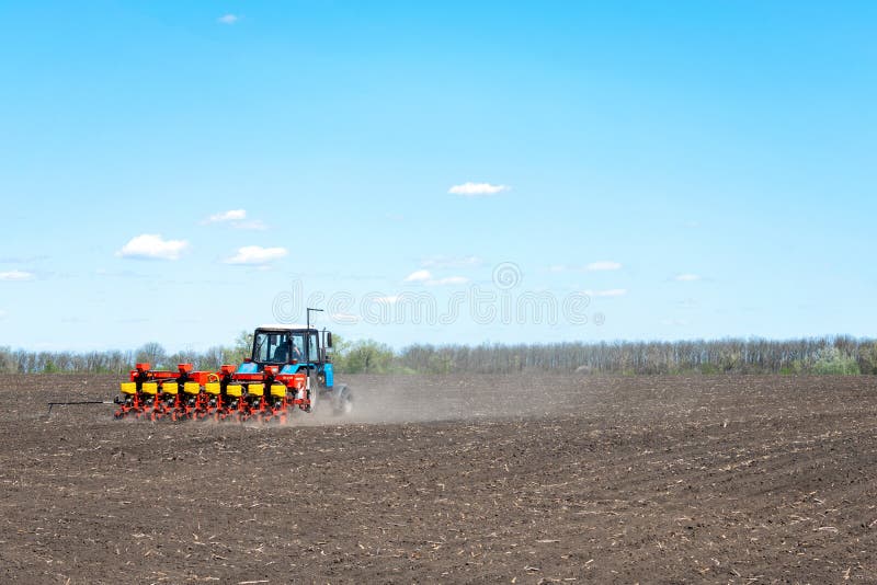 Kropivnitskiy, Ukraine â€“ 12 may, 2018: tractor sows corn on a plowed field on a sunny day. tractor seeding - sowing crops at