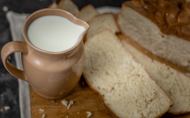 Kruik melk en een brood van brood op een houten raad stock fotografie Kruik melk en een brood van brood op een houten raad stock fotografie