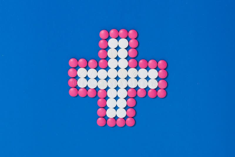 Kruis van roze en witte pillen op blauwe achtergrond stock afbeeldingen Kruis van roze en witte pillen op blauwe achtergrond stock afbeeldingen