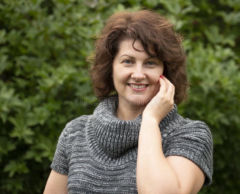 Krullende vrouw in grijze sweater op de aard stock afbeelding Krullende vrouw in grijze sweater op de aard stock afbeelding
