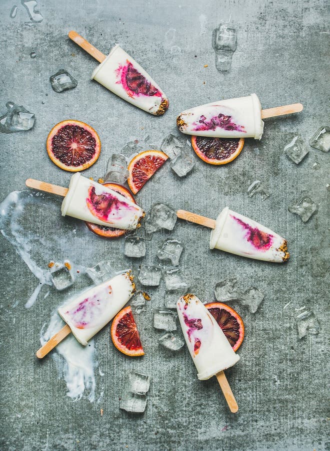 Krwionośnej pomarańcze, jogurtu i granola popsicles na lodzie, betonowy tło obrazy stock Krwionośnej pomarańcze, jogurtu i granola popsicles na lodzie, betonowy tło obrazy stock