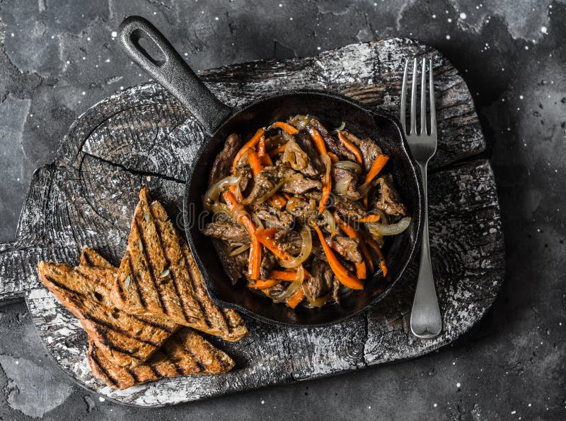 Kryddigt stekt nötkött wokar med sichuan peppar, morötter, lökar i stekpannan på en mörk bakgrund, bästa sikt arkivbild Kryddigt stekt nötkött wokar med sichuan peppar, morötter, lökar i stekpannan på en mörk bakgrund, bästa sikt arkivbild