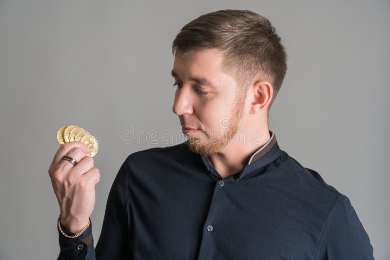 Krypto-Anleger halten in seiner Hand eine Menge BTC-Goldmünzen auf grauem Hintergrund stockfoto